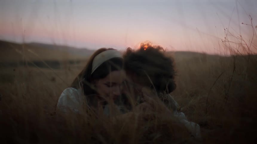 Couple sitting together romantically in a field in the late afternoon