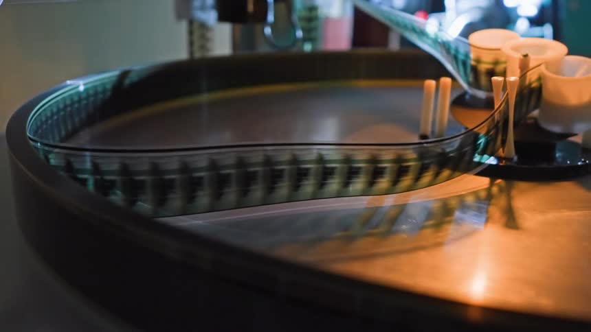 Closeup of film moving through a film machine with multiple rotating parts