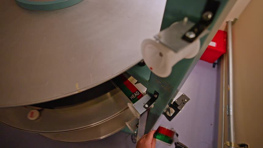 A hand guiding a strip of film through a film projector or a digital scanner