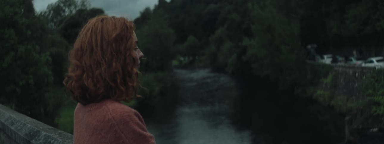 A woman is looking at the river on a windy day