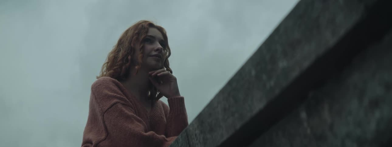 A young woman with red hair stands on staircase modeling for the camera