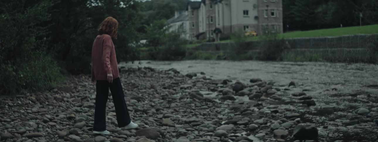 Woman walking on rocks towards a river