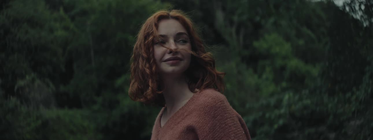 A woman with red hair smiles outside