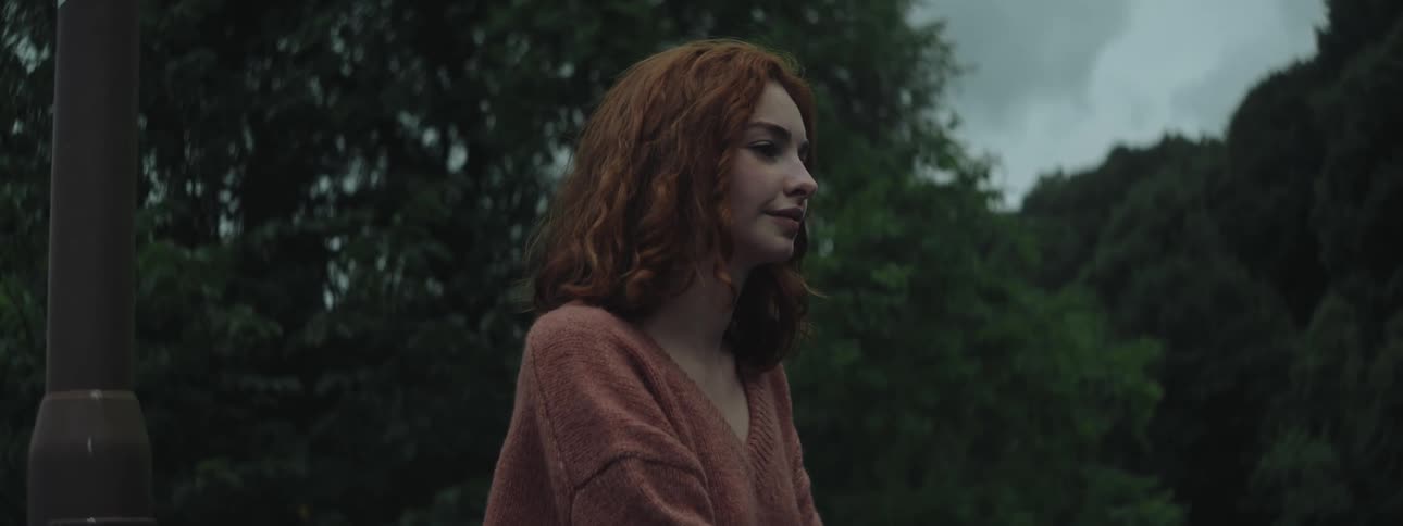 Portrait of a young woman with a happy facial expression in a treelined environment on a cloudy day