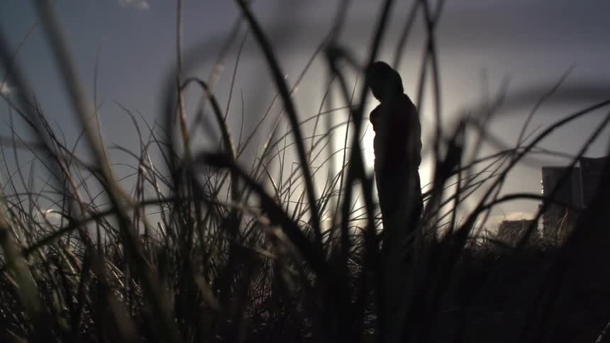 Two children in a field silhouetted against a sunny sky