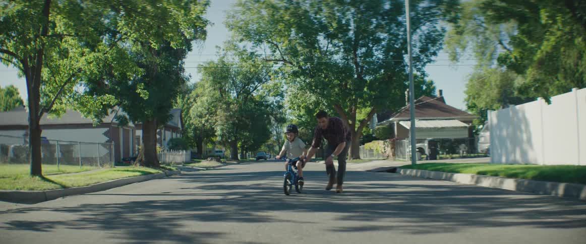 A clip of a father tutoring a son on how to ride a bicycle