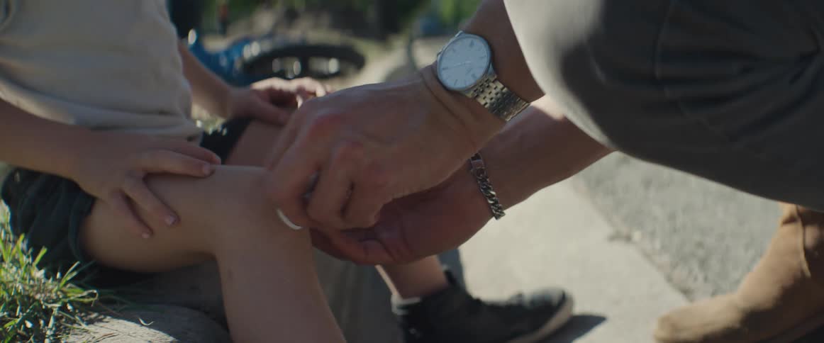 A father puts a bandage on his sons knee