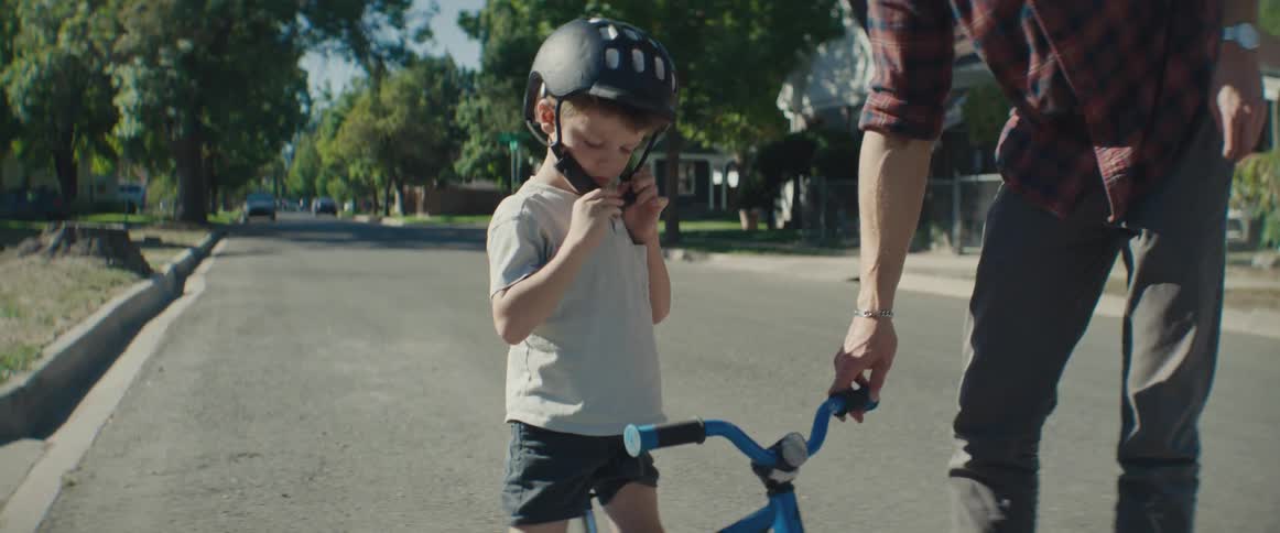 A child puts on his helmet to ride his bike