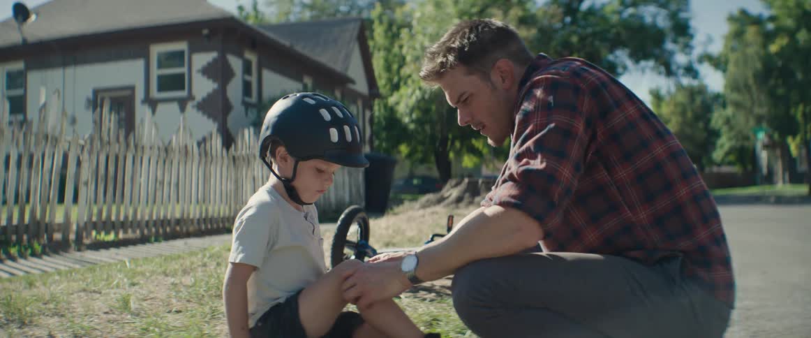 A father puts a bandage on his sons knee and then has his son give him a high five