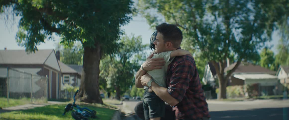 A father hugs his young son in a suburban street