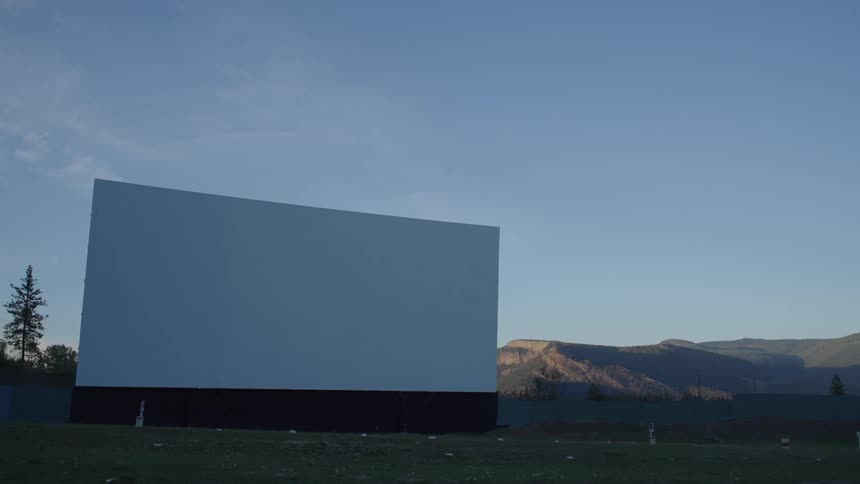 Large white sign on a fence in a field with mountains in the background