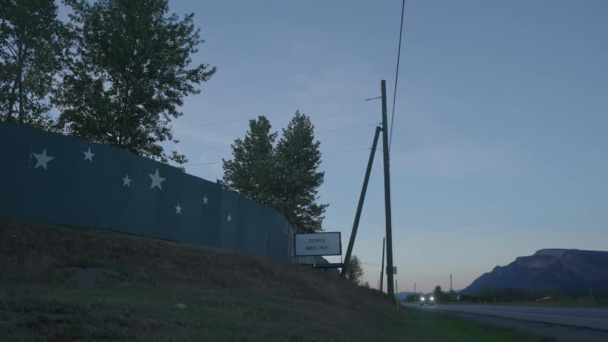 A blue fence with stars next to a road and a sign saying an establishment is closed