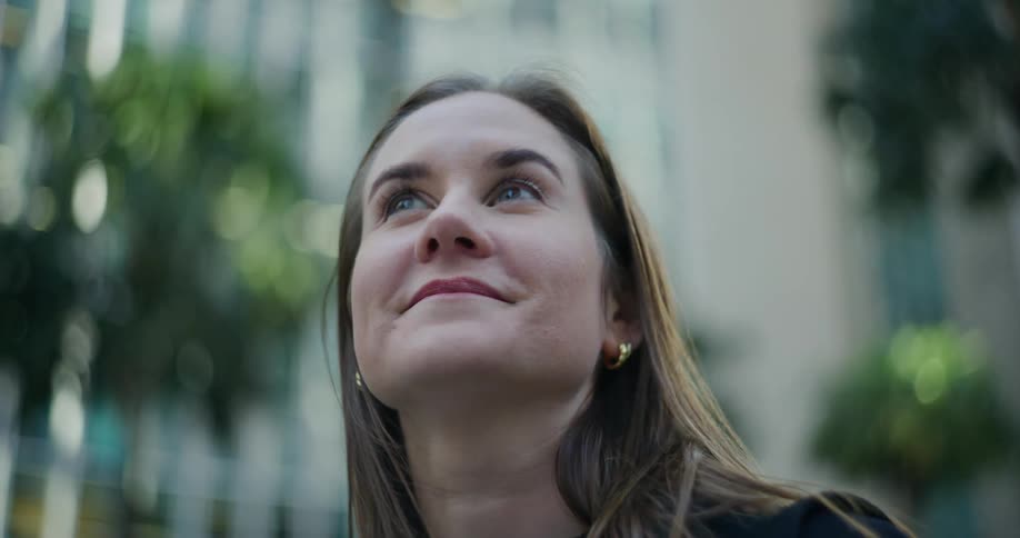 Woman standing downtown on a windy day looks around while smiling