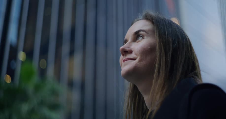 A woman with long straight hair gazes up at the citys skyscrapers