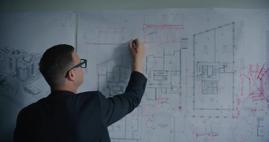 An architect is drawing on blueprints