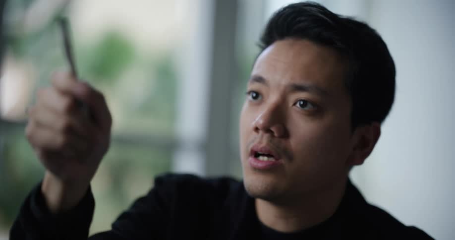 Portrait of a man holding a pen and making gestures while talking