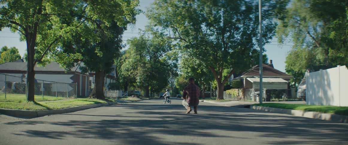 A father watches his son riding a bike and then runs over to the boy