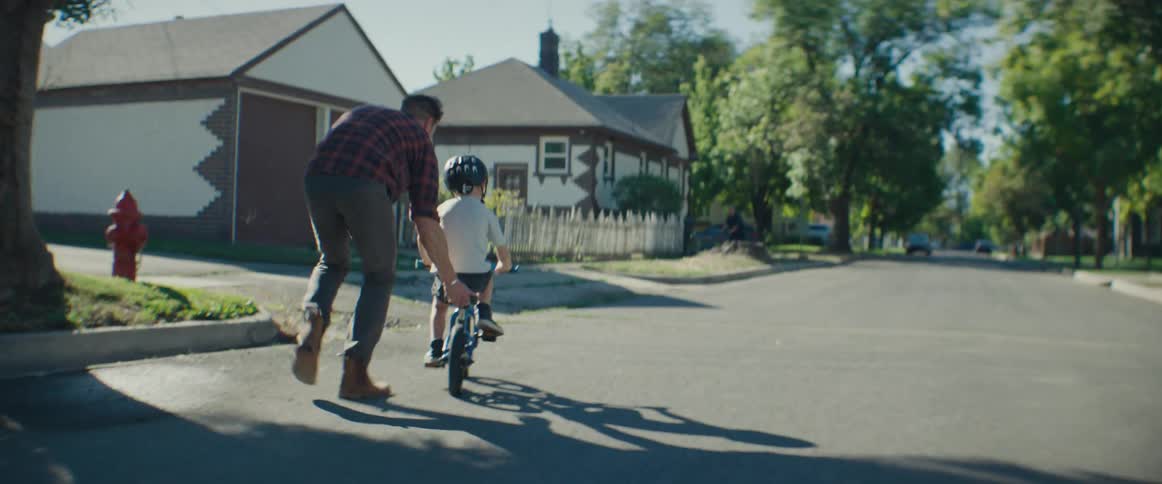 A father is helping his son ride a bicycle
