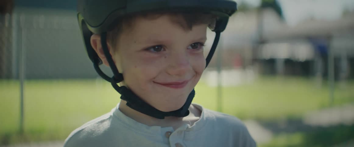 Boy in helmet with a sullen and then happy face interacting with his father