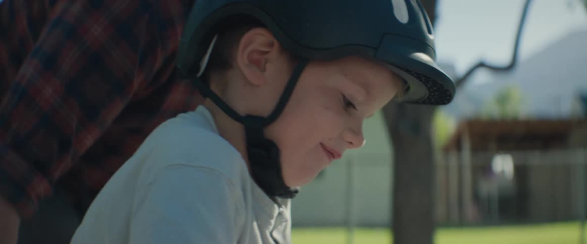 Father teaches his son how to ride a bicycle on a street in their residential neighborhood