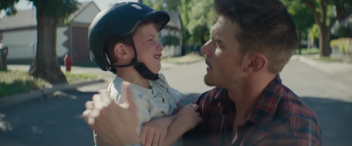 A father consoling his crying son on a suburban road