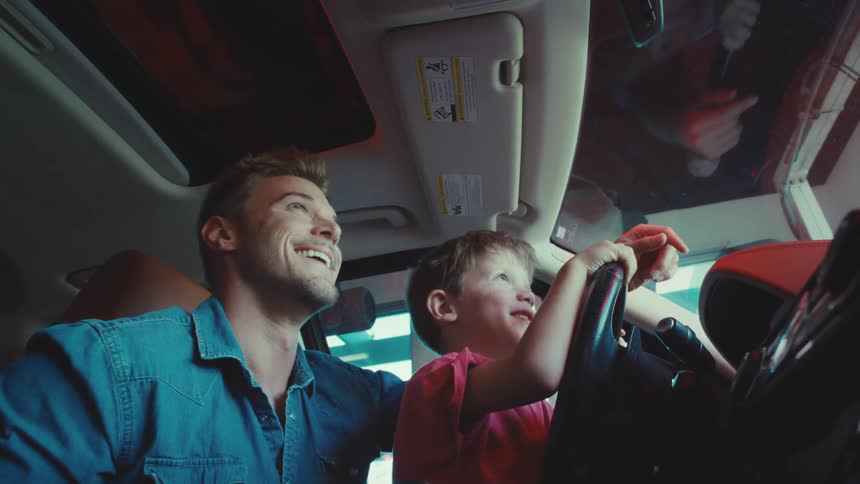 Father driving the car with his little son and both are happy