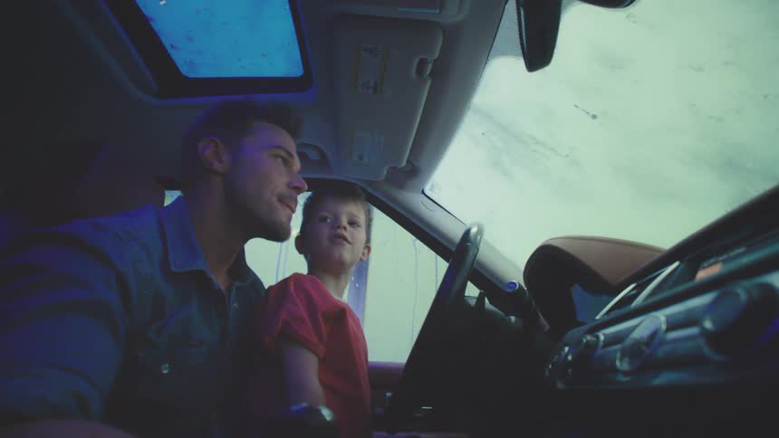 Father with his young son inside the car while the car is being washed