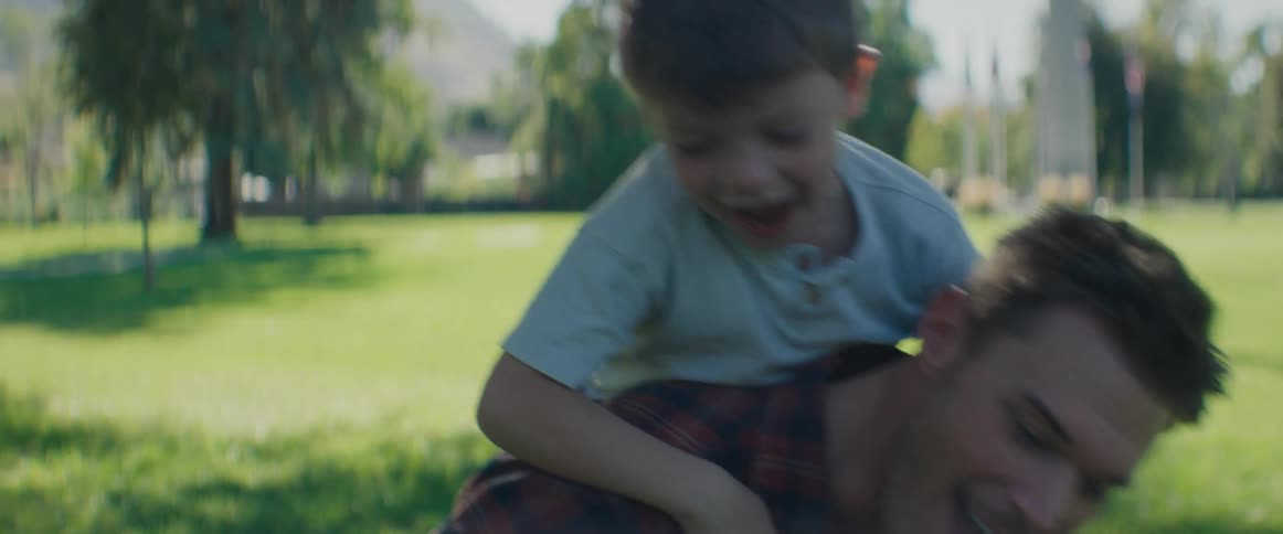 A father laughs as his son gives him a piggyback ride