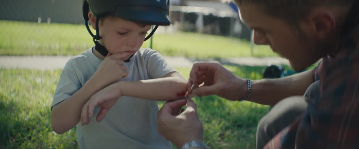 A father puts a bandage on his sons scraped elbow