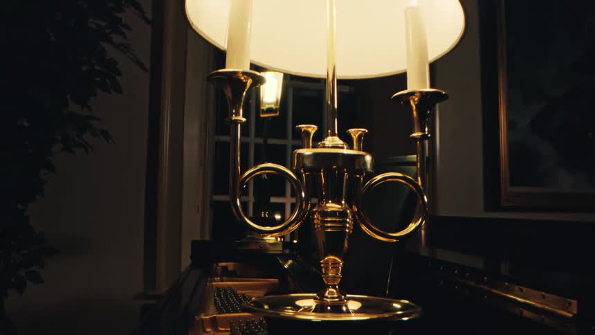 A golden candelabra with some candles lit on it and it is on top of a large wooden table