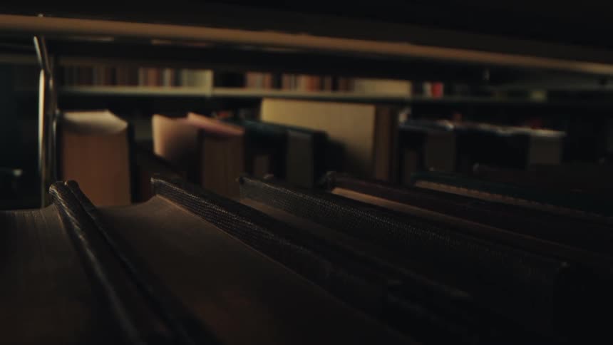 Books line double sided bookcases in a dimly lit area