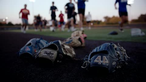 Baseball gloves lying on the field and people running in the background