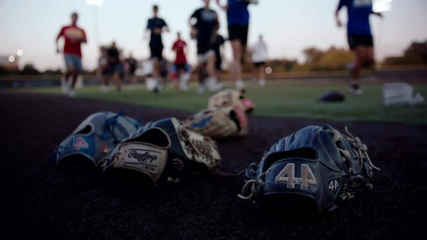 Baseball gloves lying on the field and people running in the background