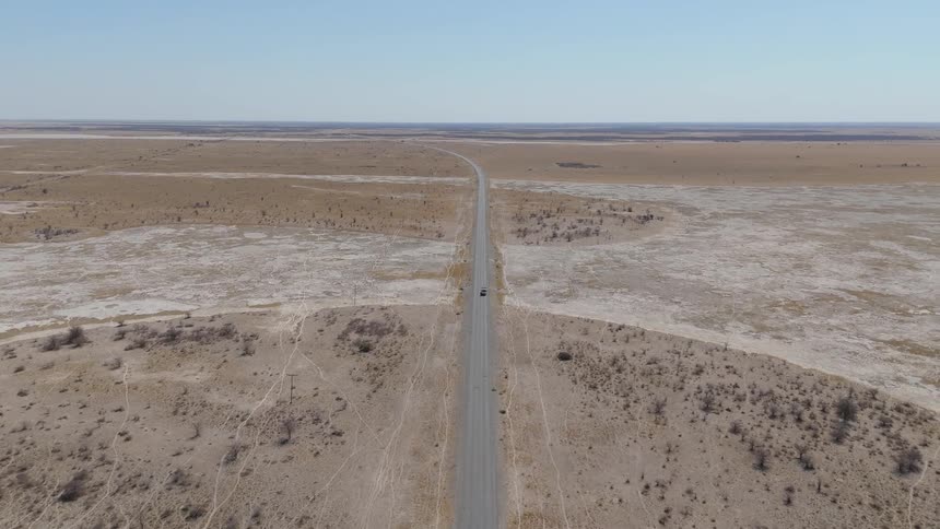 Aerial view of a long highway surrounded by dry vegetation