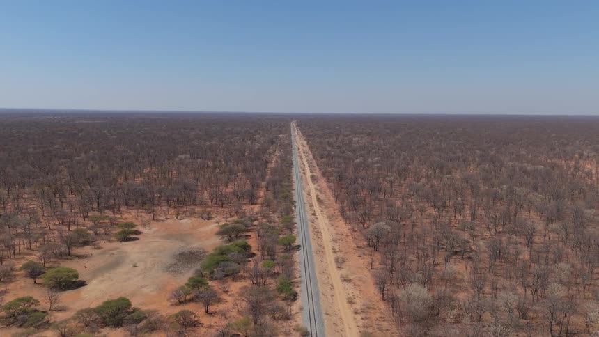 Long straight road cuts through a dry sparsely vegetated landscape
