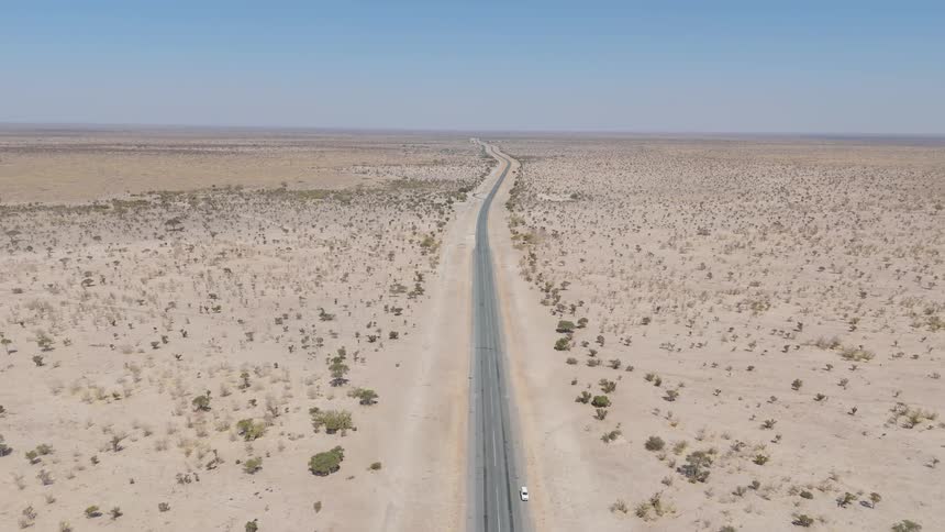A long straight road stretching into the distance through a vast arid desert landscape