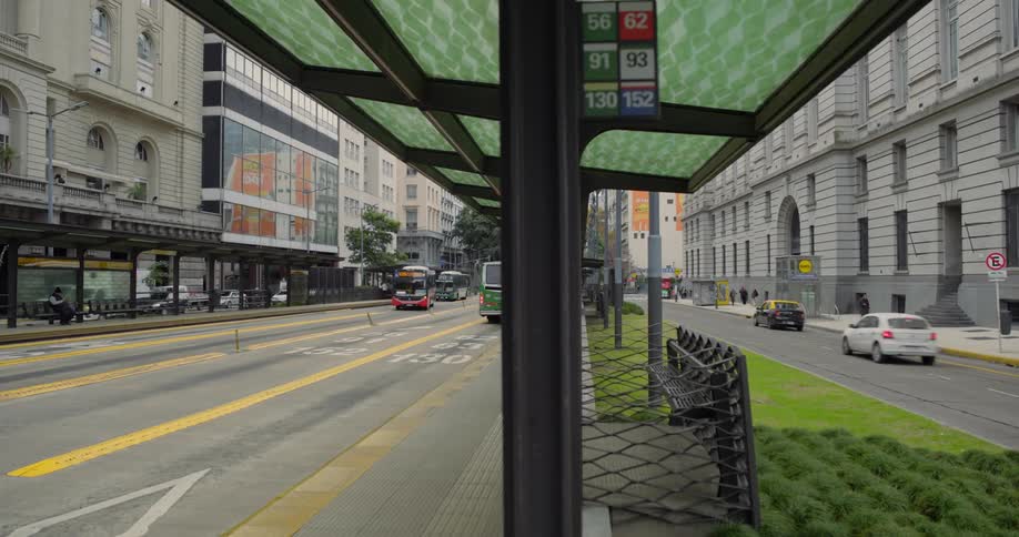 Vehicles drive on opposite sides of a street lined with shops and other attached buildings
