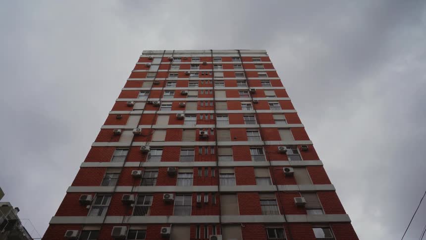 A red apartment building rises into the sky in a city