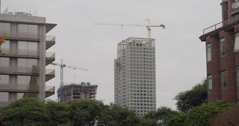 A tall white tower is shown between an office building and a brick building