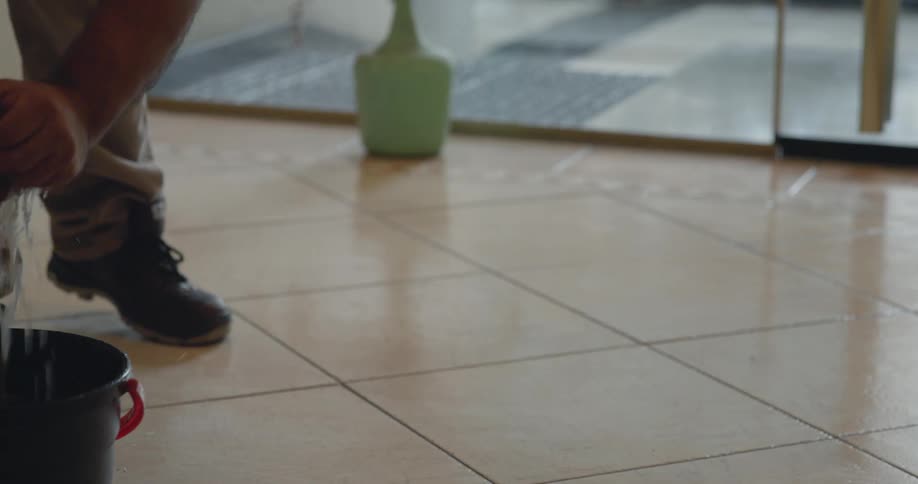 Person with a squeegee and cloth wiping a wet floor