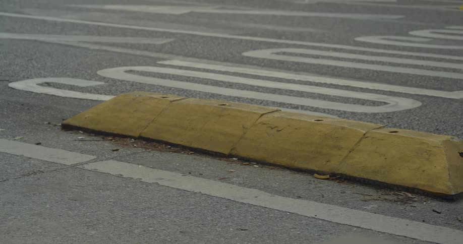 Yellow divider located on a paved street with vehicle traffic
