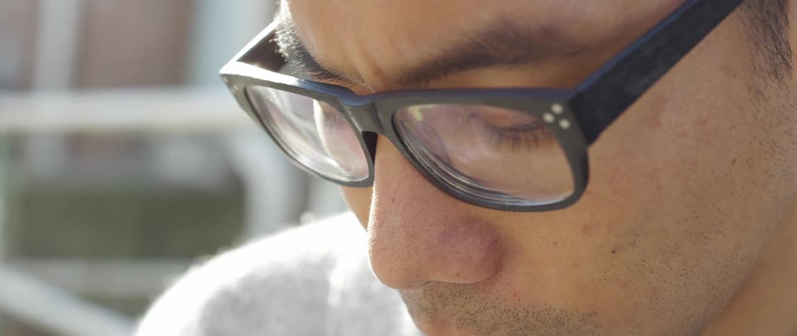 Man wearing glasses looking down on a sunny day