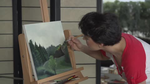 A short-haired woman painting a nature scene