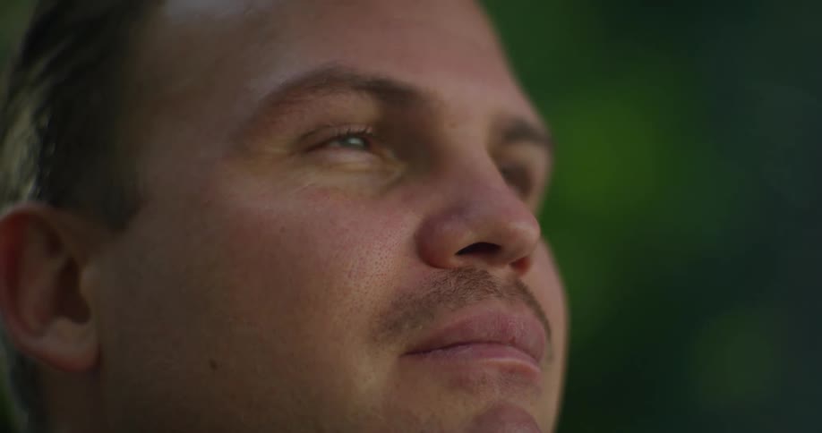 Man with a mustache looks around outdoors