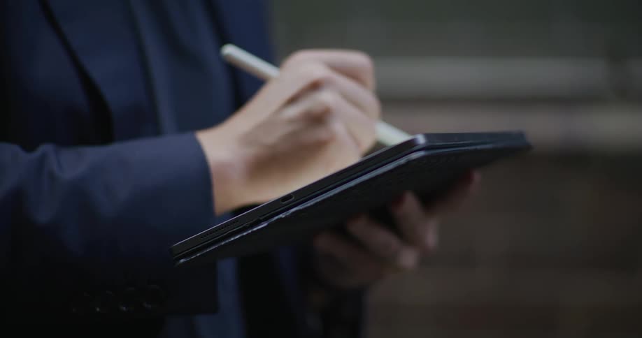 Hand with a pen writing on a tablet