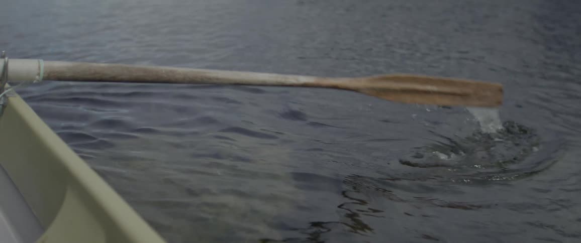 Wooden oar moving across a calm lake