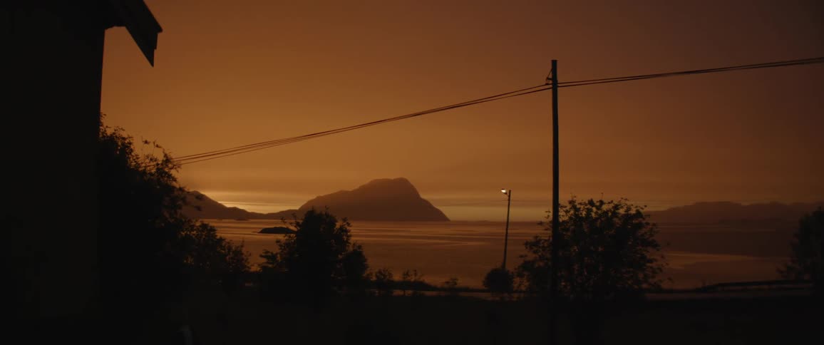 The shore of the lake is dark at sunset