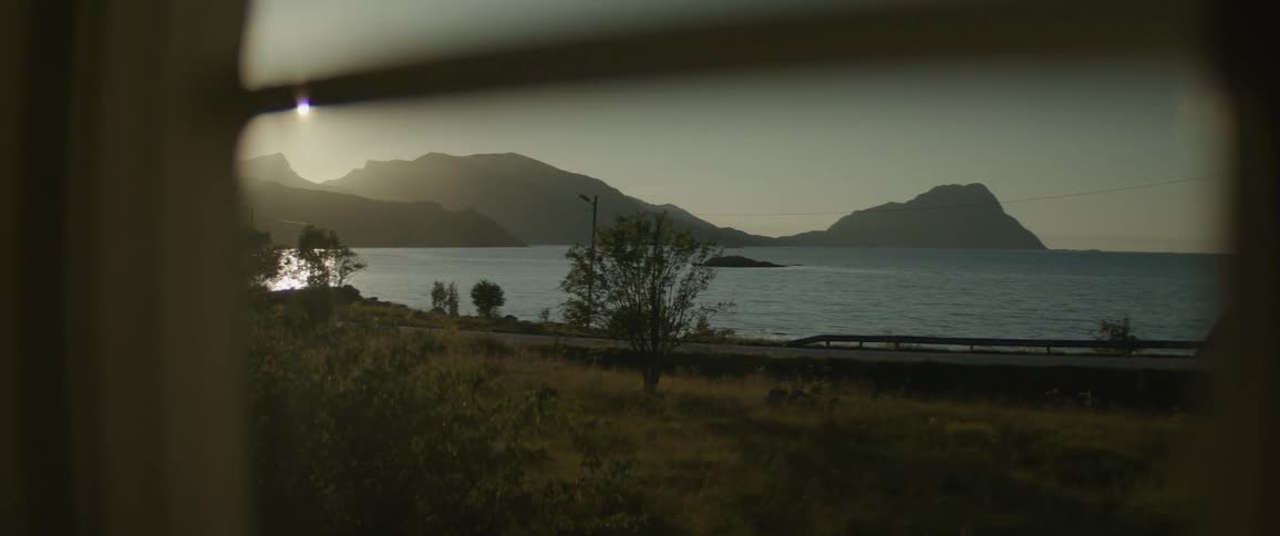 A view of a body of water and mountains seen through a window
