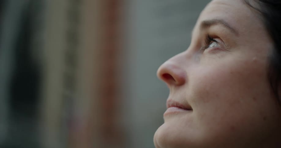 Woman standing outdoors on a windy day smiles while looking up