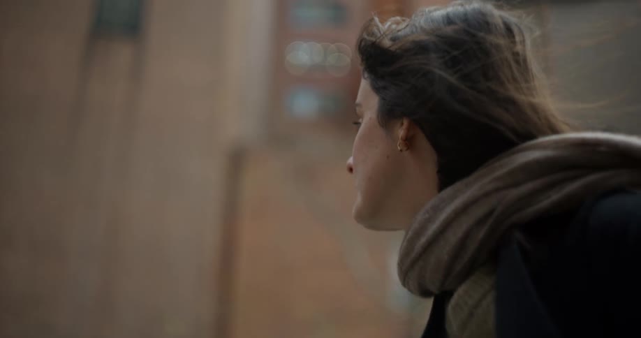 A woman wearng a scarf and coat walking down a city street